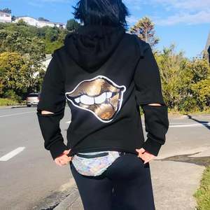 Kelly wears our Gold Lips Sequin hoodie walking in Wellington, NZ