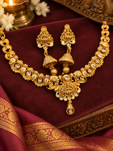 Jewellery: Elegant matte gold-finish Temple Jewellery Set Goddess Lakshmi motif with beautifully detailed elephant designs and stone accents. Comes with matching jhumka earrings(slight variation in color & design may occur)