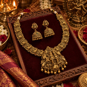 Jewellery: Elegant matte gold-finish Temple Jewellery Set featuring an intricate Krishna motif with beautifully detailed elephant designs and green stone accents. Comes with matching jhumka earrings(slight variation in color & design may occur)